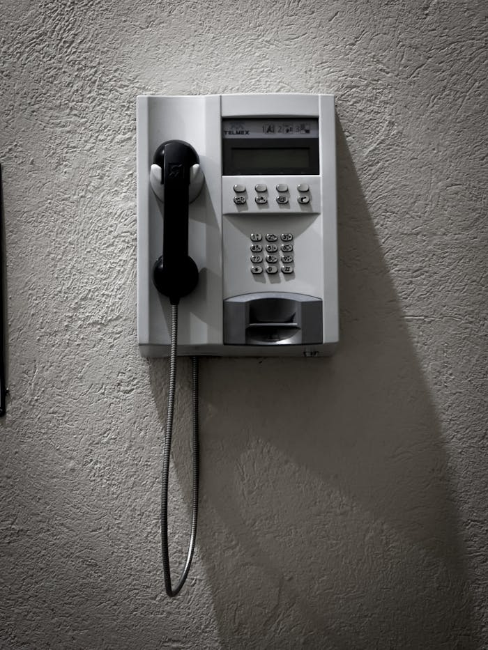 Close-up of a vintage wall-mounted telephone with a hanging receiver and keypad.